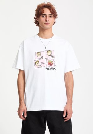 T-shirt en coton blanc avec un graphique coloré représentant quatre visages de dessins animés et le texte "CHOMP CHOMP" et "VOLCOM" au bas.