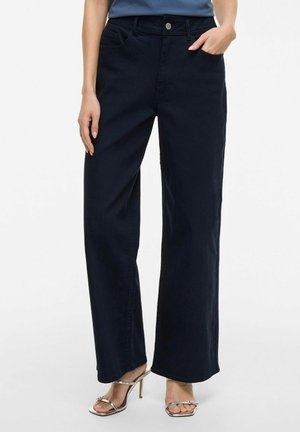 Wide-leg, dark navy trousers made of cotton fabric. Features a front button closure, belt loops, and side pockets. Smooth texture.