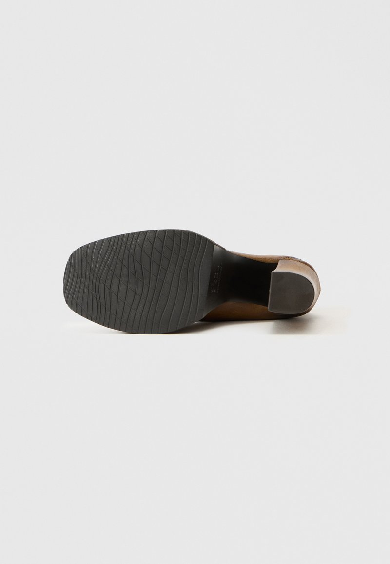 Semelle en cuir marron avec une semelle extérieure en caoutchouc noir texturé. Présente un talon arrondi et un design épuré et minimaliste.