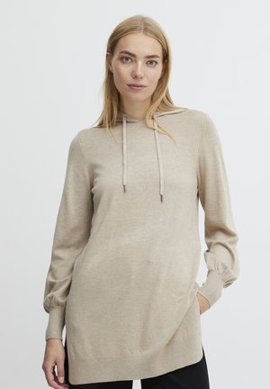 Pull en tricot beige avec capuche, manches longues et poignets ajustés. Texture lisse, coupe décontractée et ourlet arrière légèrement plus long.