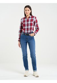 Sarkans un balts ķekars krekliņš ar garām piedurknēm, apvienots ar ziliem augsto jostu džinsiem un baltām kedām. Iekļauts melns jostas siksna.