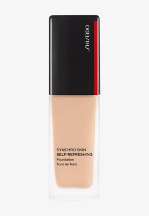 Shiseido Synchro Skin Self-Refreshing foundation i en gjennomsiktig flaske med svart og rød hette, med mørk tekst på en beige væske.