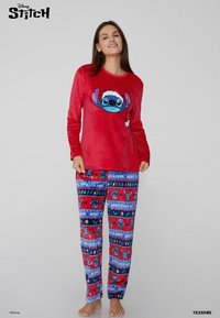 Top de pijama de manga larga rojo con gráfico de Stitch con gorro de Santa; pantalones de pijama azules, rojos y estampados con diseños festivos.