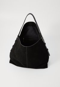 Zwarte suède schoudertas met een soepele leren handvat, binnenzak met rits en een afgeronde vorm. De textuur is zacht met minimale detailing.