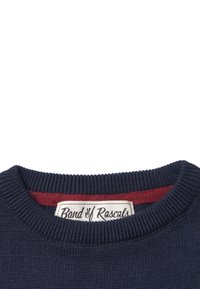 Merino villapaidat tummansinisellä värillä, jossa on ribattua kaulusta ja maroonin värinen vuori, sisältäen kudotun lapun, jossa lukee "Banda Rascals".