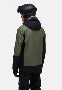 Skijacke in Dunkelgrün und Schwarz, aus wasserdichtem Material gefertigt. Verfügt über eine Kapuze, ein Logo auf dem Rücken und verstellbare Bündchen.