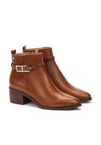 Bottines en cuir marron avec un bout pointu, un petit talon carré, un détail de boucle dorée, et une languette à l'arrière pour un enfilage facile.