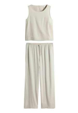 Bezruký béžový crop top s okrúhlym výstrihom a zodpovedajúce voľné béžové nohavice s elastickým pásom a šnúrkou.