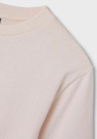 T-shirt rosa chiaro con collo tondo, maniche corte e una texture morbida e liscia. Il tessuto sembra traspirante e leggero.