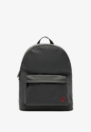 Sac à dos en nylon noir avec un haut arrondi, doté d'une poche zippée à l'avant, d'une texture lisse et d'un petit logo rouge dans le coin inférieur droit.