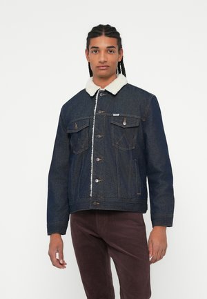 Tume denim jakker, millel on valge karusnahast krae, ees klapptaskud ja metallnupud. Omab tavalist lõiget ja veidi tekstureeritud kangast.