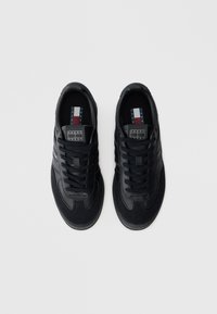 Fekete Tommy Jeans cipőpár fűzőkkel, felülről nézve, egyszínű fehér háttéren.