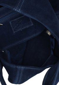 Marineblauwe suède handtas met een gestructureerd oppervlak, binnenzak en een label met de tekst "Made in Italy." Voorzien van stevige stiksels en metalen accenten.