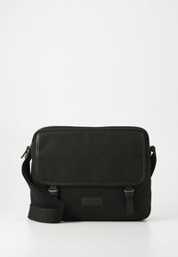 Borsa a tracolla nera realizzata in tessuto resistente, dotata di chiusura a patella, tracolla regolabile e dettaglio del logo discreto sul davanti.