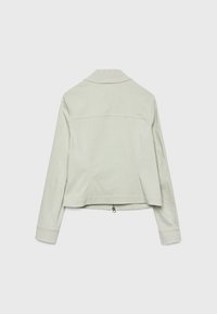 Lysegrå jakke med krave, lange ærmer og en let udvidet kant. Har en lynlåsdetaile i bunden og en glat tekstur.