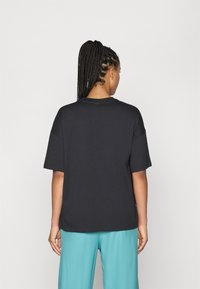 Zwarte katoenen t-shirt met korte mouwen, ronde hals en een ontspannen pasvorm. Het heeft een effen ontwerp zonder zichtbare patronen of accenten.