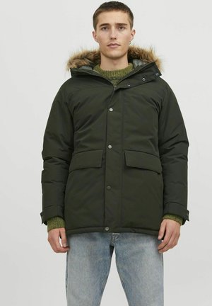 Dark green padded jacket with a fur-trimmed hood, snap buttons, two front pockets, and elastic cuffs. Worn over a green knit sweater.