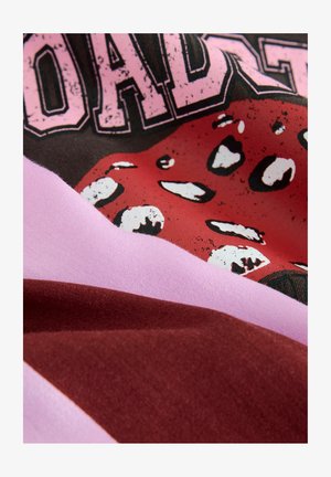Grafischer Druckstoff mit einem roten Zungenmotiv auf schwarzem Hintergrund, kombiniert mit pinken und burgunderfarbenen Stoffabschnitten. Weiche Textur.