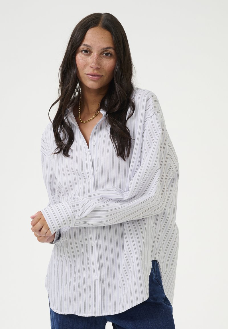 White striped shirt with blue lines, button front, wide cuffs, and a relaxed fit. Soft fabric with a slight sheen.