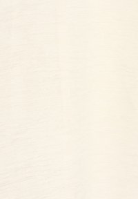 Gros plan d’un tissu crème texturé avec des lignes horizontales subtiles et un motif de tissage doux et irrégulier.