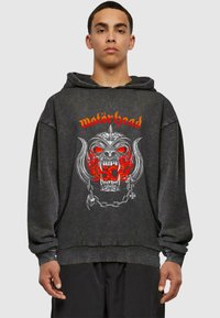 Čierna mikina s kapucňou featuring veľký grafický dizajn lebky s červenými akcentmi a kovovými detailmi, logo znie "motörhead."