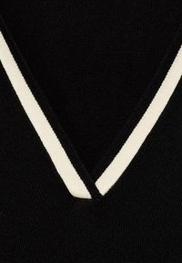 Tessuto lavorato a maglia nero con scollatura a V e bordo bianco a contrasto lungo il margine, che mette in risalto il suo aspetto strutturato.