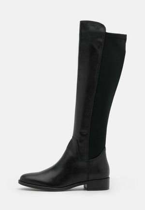 Stivale da equitazione nero fino al ginocchio con parte anteriore in pelle, retro in tessuto elasticizzato, punta arrotondata e tacco basso a blocco su sfondo grigio chiaro uniforme.