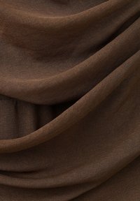 Tissu marron doux avec des plis lisses et une texture finement tissée en gros plan.