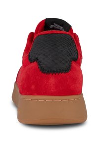 Crvene zamšaste cipele s teksturiranim crnim kožnim petnim detaljem, koji ima uzdignuti uzorak, i smešnim gumiranim đonom.