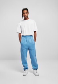 Lichtblauwe trainingsbroek met een elastische tailleband, cuffed enkels en zijzakken, gecombineerd met een eenvoudige witte t-shirt met korte mouwen.