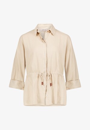 Chemise beige à manches longues avec fermeture boutonnée sur le devant, poignets retroussés, col et taille ajustable avec cordon à embouts en bois.