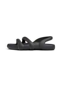 Black, flexible sandals featuring a wavy design with multiple cut-outs and a flat sole, made of smooth, rubber-like material.