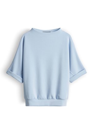 Felpa a maniche corte color azzurro con polsini risvoltati, scollo rotondo e orlo elastico, mostrata su sfondo bianco.