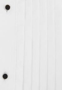 Țesătură albă cu pliuri verticale și accente de nasturi negri. Textura este netedă, creând un aspect curat și minimalist.