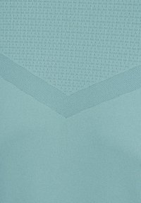 Tejido de punto azul claro con patrones de textura variados que forman una forma de V y pequeños puntos en relieve en la sección superior.