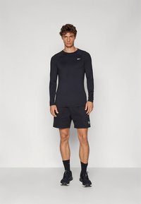 Must pika varrukaga sportlik särk ümara kaelusega, sellega koos mustad lühikesed püksid. Mõlemal riideesemel on peen logo. Kandmisel mustad sokid ja spordijalatsid.