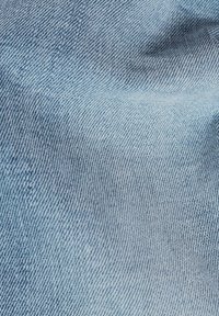 Světlé modré džínové plátno s jemným diagonálním vzorem tkaní. Textura působí měkce, hladce a mírně opotřebovaně.