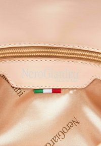 Perzikkleurige leren tasinterieur met een gouden rits, een label met de tekst "NeroGiardini" en een klein Italiaans vlaggetje. Satijnen voering.