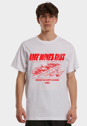 Ung mann iført en hvit T-skjorte med rød tekst "LIFE MOVES FAST" og et samlebånd av matillustrasjoner.