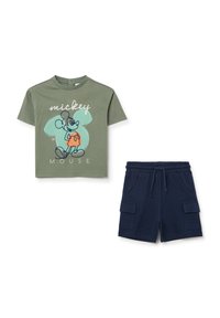 Camiseta de algodón verde oliva con un gráfico de Mickey Mouse y un contorno azul claro; combinada con pantalones cortos azul marino que tienen bolsillos laterales y una cinturilla elástica.