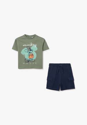 Olivgrünes Baumwoll-T-Shirt mit einem Mickey-Mouse-Graphic und hellblauer Umrandung; kombiniert mit marineblauen Shorts mit Cargo-Taschen und elastischem Bund.