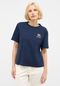 T-shirt en coton bleu marine à manches courtes et col rond, arborant un logo de crabe et du texte sur le côté gauche de la poitrine.
