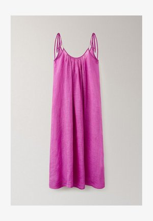 Vestito lungo senza maniche in lino rosa con sottili spalline regolabili e scollo arricciato, appeso a una parete chiara e semplice.