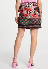 Kleurijke bloemen mini-rok met een zwarte basis en patronen in rood, groen en roze. Inclusief een decoratieve tailleband en accentuerende zoom.