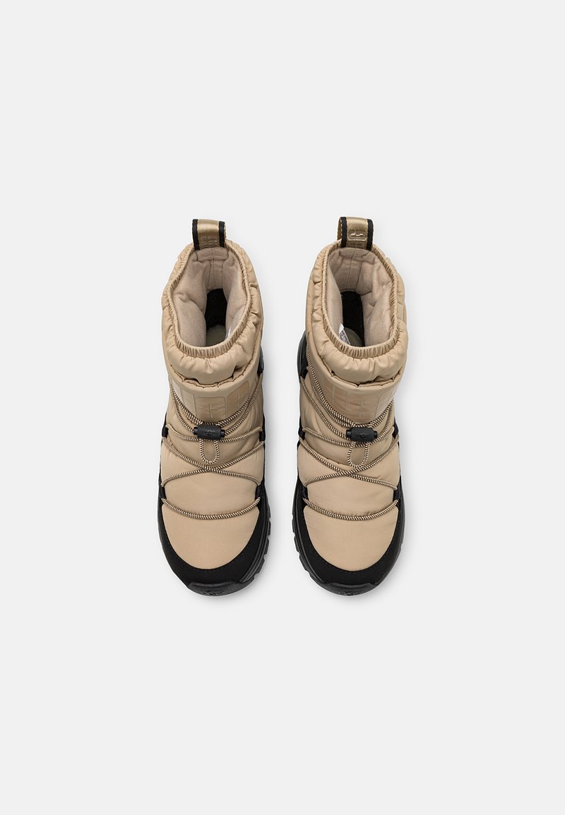 Ein Paar beige und schwarze, isolierte Winterstiefel mit gepolsterten Kragen und elastischen Zuglaschen, von oben auf weißem Hintergrund betrachtet.