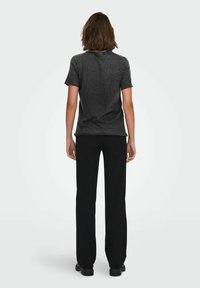 Camiseta negra de manga corta con una textura ligeramente áspera, combinada con pantalones negros de pierna recta. Diseño simple, con un mínimo de detalles.