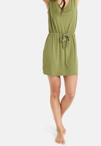 Vihreä oliivinvärinen hihaton mekko, jossa on säädettävä nauhavyötärö, polven ylle ulottuva pituus, pehmeä kangas ja yksinkertainen muotoilu.