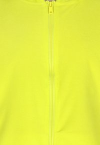 Tessuto in pile giallo fluorescente con una cerniera centrale, caratterizzato da una superficie testurizzata e un cursore della cerniera chiaro in contrasto.