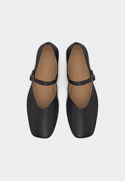Paire de ballerines Mary Jane en cuir noir avec bouts carrés et semelles intérieures rembourrées couleur beige, vues de dessus sur un fond blanc.