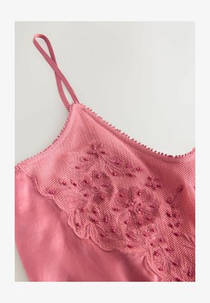 Rosa linne med justerbara axelband, med en strukturerad broderad spetsdesign och pärldetaljer på framsidan. Slätt satinliknande tyg.